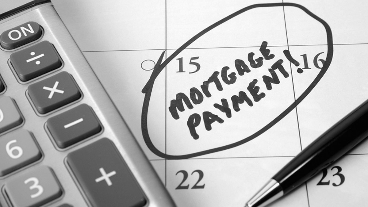计算器和笔旁边的日历上，圈出了写着 MORTGAGE PAYMENT 的一天