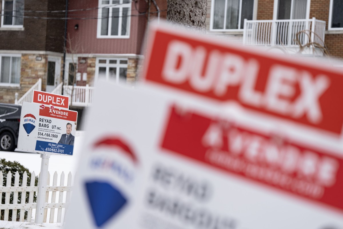 住宅街上一块写着「DUPLEX À VENDRE」的地产经纪牌子，背景是砖砌住宅