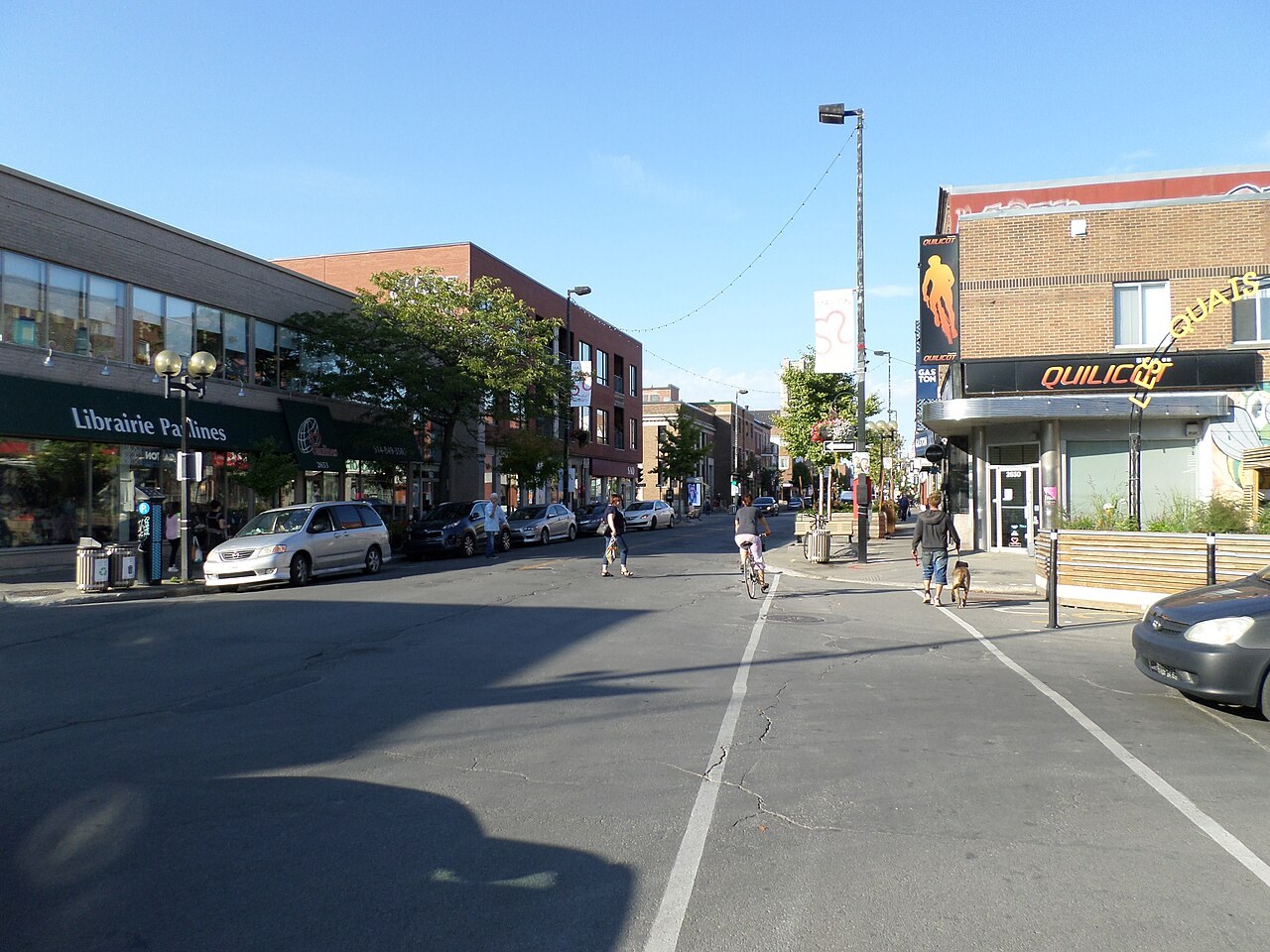 蒙特利尔 Rosemont 区的 Masson 街，两边是书店、商铺和砖楼，行人和骑车人走在街上