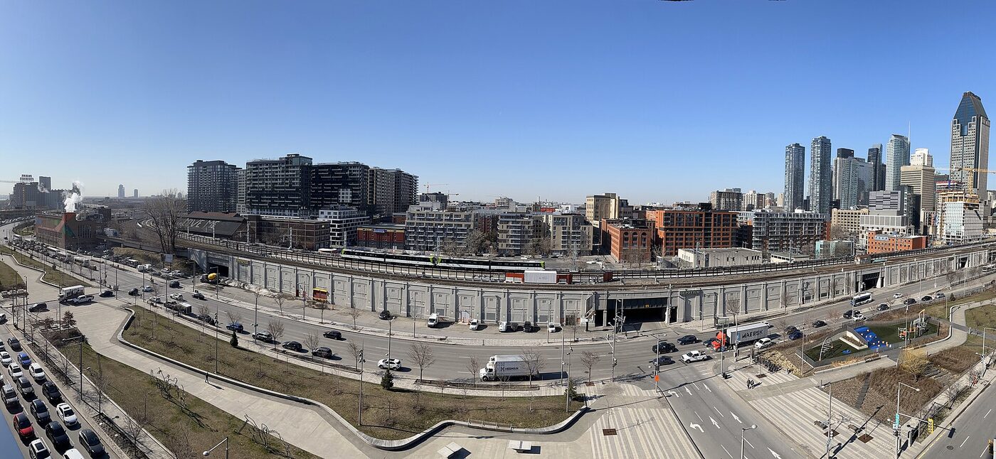 REM 列车经过 Griffintown 一段高架，两侧是新建公寓楼，远处是蒙特利尔市中心